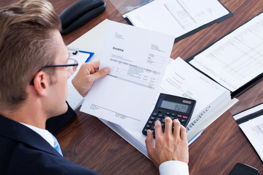 A man sitting at a table with papers and a calculator.