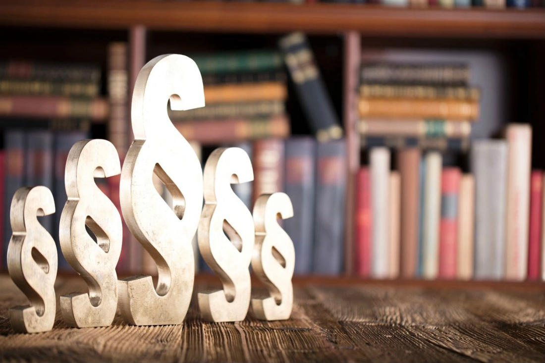 A wooden dollar sign sitting in front of some books.