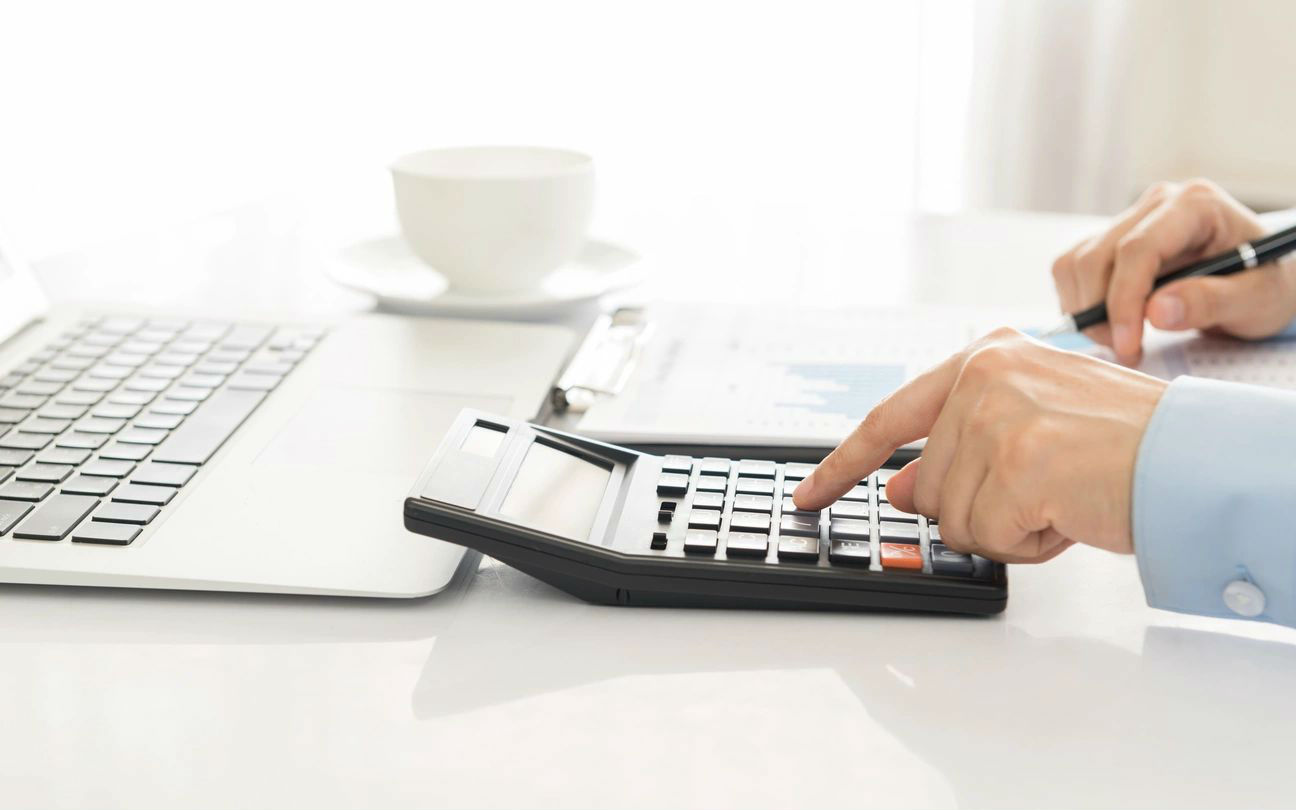 A person using a calculator on top of a desk.